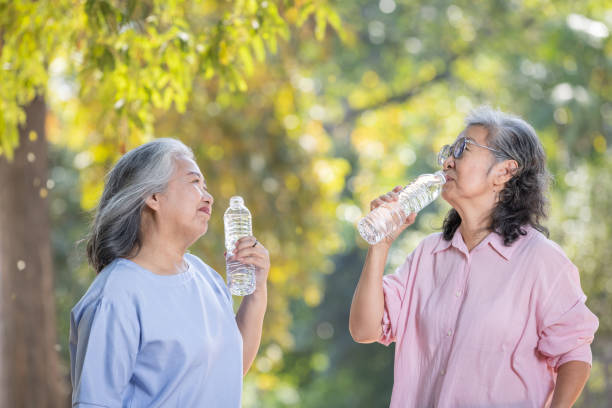 istock two asian elderly women with water bottle drinking water from bottle. 1944329644