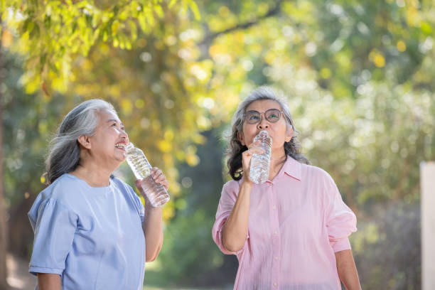 istock senior women drinking water from bottle while walking in the park 1944330147