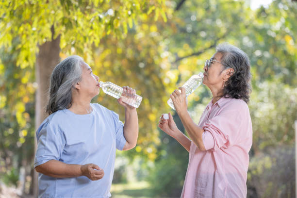 istock two asian elderly women with water bottle drinking water from bottle. 1944330152