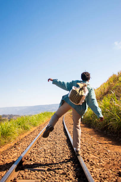 A young solo traveller  walking  along the rail playfully