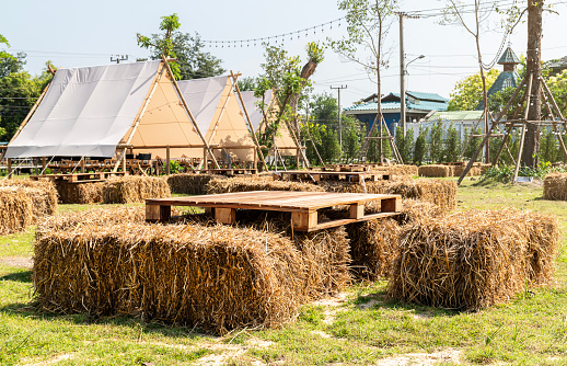 Straw seats and pallet wood table and outdoor living tent on lawn