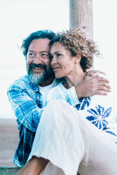 blue mood of romantic couple enjoy time together outdoor with winter beach in background. concept of relationship and travel people. intimacy and love between adult mature man and woman - honeymoon beach couple heterosexual couple fotografías e imágenes de stock