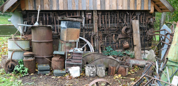Rusty tools barrels and canisters thrown near a wooden  shed