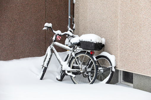 Bicycles at the wall of the house after a snowfall, winter time.