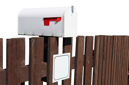 Metal mailbox mounted on a rustic  fence. Isolated on white