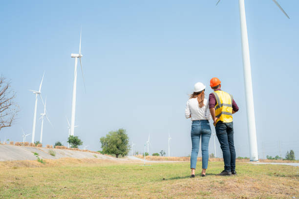 istock Back view of engineer and architect on construction site with wind turbines in background 1944416598