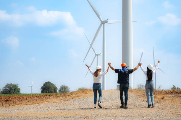 istock Back view of group engineers walking and looking at wind turbines in a windmill farm. 1944422375
