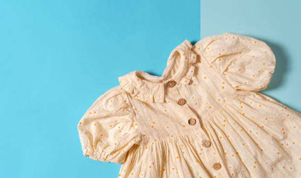 Top view flat lay natural textile child dress on blue background. Copy space.