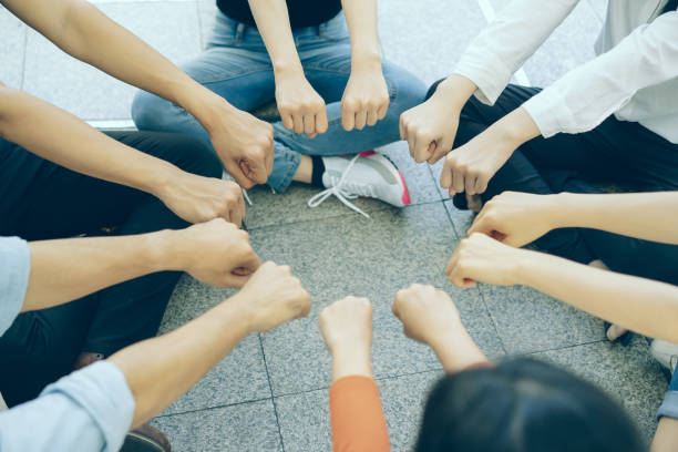 grupo de jóvenes juntando sus puños en un concepto circular en la parte superior del piso. concepto de confianza, amistad, unidad, cooperación. - youth organization fotografías e imágenes de stock