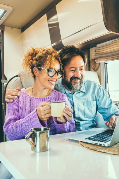 istock Modern couple use together laptop inside camper van. Computer leisure people surfing the web. Traveler planning next destination smiling and enjoying freedom living off grid. Digital nomad concept 1944464010
