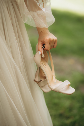 The bride on a walk holding shoes in her hands. High quality photo