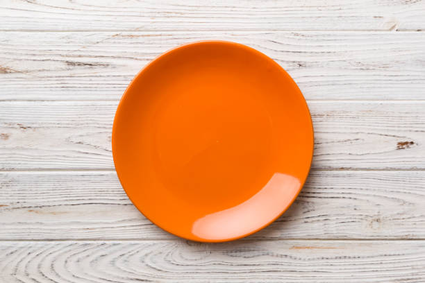 istock Top view of empty orange plate on wooden background. Empty space for your design 1944494656