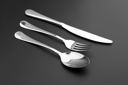 Fork, knife and spoon on black background