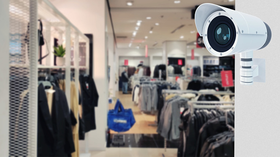 CCTV camera in store against the blured background of a clothing store. Security video system.