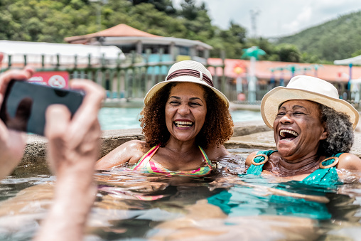 Person taking photos of mother and daughter at water park swimming pool