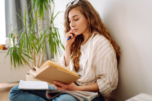 istock Young woman reading a book, writing notes, doing homework at home. 1944525201