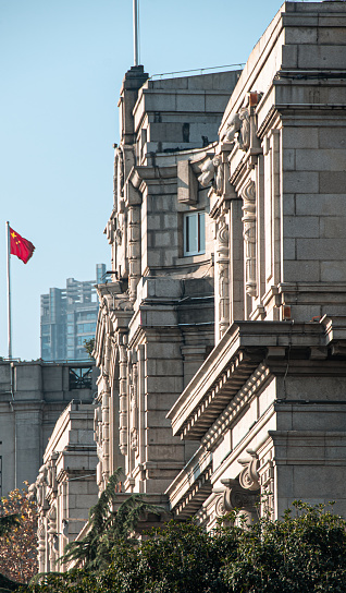 A majestic stone edifice with a flag gracefully waving on its facade. Wuhan, China