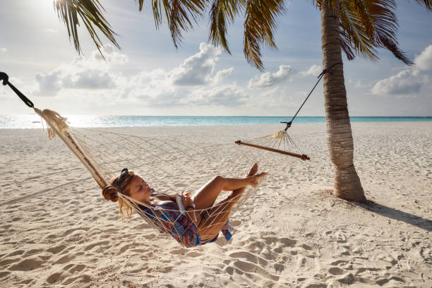 istock Relaxed woman spending a summer day in hammock on the beach. 1944547940