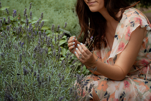 Young woman portrait smiling while smelling lavender bush