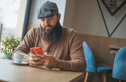 Handsome hipster guy using smart phone in cafe