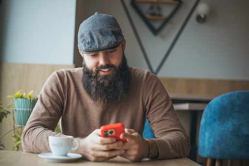 Handsome hipster guy using smart phone in cafe