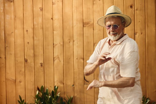 Portrait of mature man having fun while dancing against brown background in the backyard. Copy space.