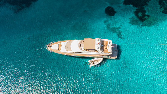 Luxury yacht on the water sea surface from top view. Turquoise water background from top view. Summer seascape from air. Travel on boat concept idea