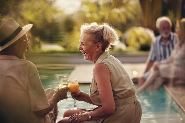 cheerful mature couple toasting by the pool in summer day. - active seniors retirement enjoyment swimming pool stock-fotos und bilder