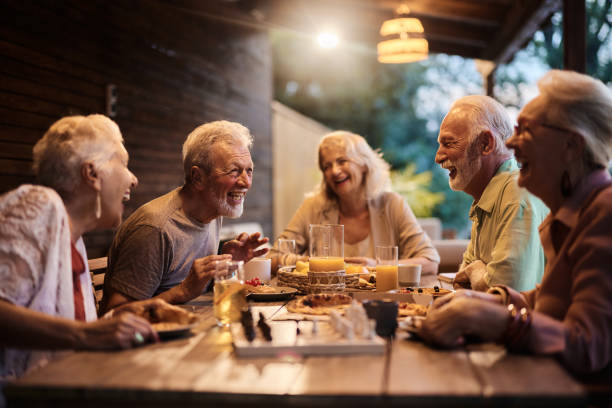 Group of cheerful seniors talking at picnic table on a patio.
