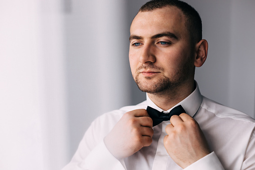 The groom in a white shirt, wears a black bow tie. Wedding concept.