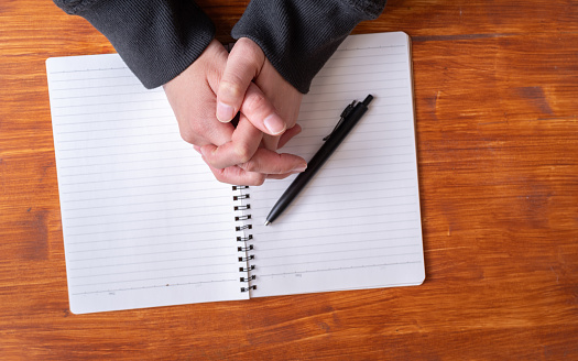 person folding hands over blank notebook