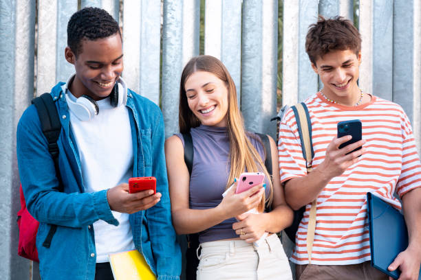 istock Multiracial Group Of Smiling Students Browsing Smartphone App Outdoors. 1944589725