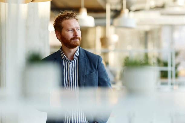 Smiling redhead businessman day dreaming in the office.