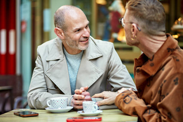 istock Mature gay couple talking over coffee at sidewalk cafe table 1944601041