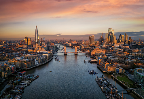 Panoramic view of the skyline of London during a sunrise with Tower Bridge and the skyscrapers of the City in golden, soft light, England
