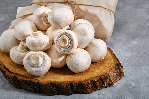 Fresh champignons on an old wooden cutting board for frying. Side view. Close-up, copy space