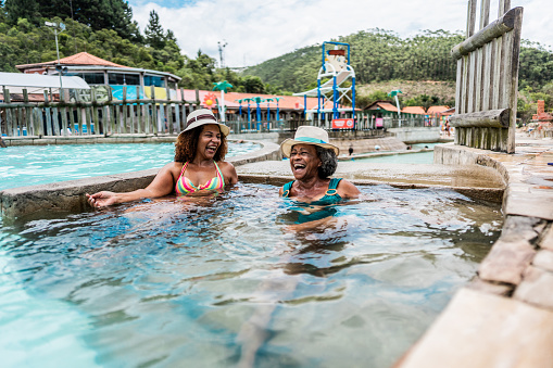 Mother and daughter talking at water park swimming pool