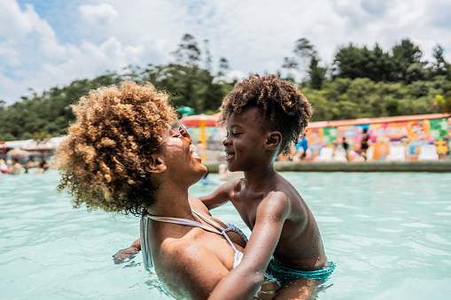 Mother playing with son at water park swimming pool