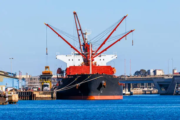 Photo of Large bulk carrier cargo ship loading/unloading at port on sunny day
