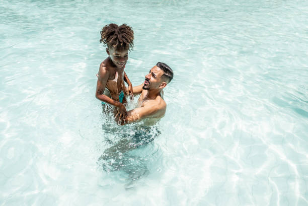 istock Father playing with son at water park swimming pool 1944667951