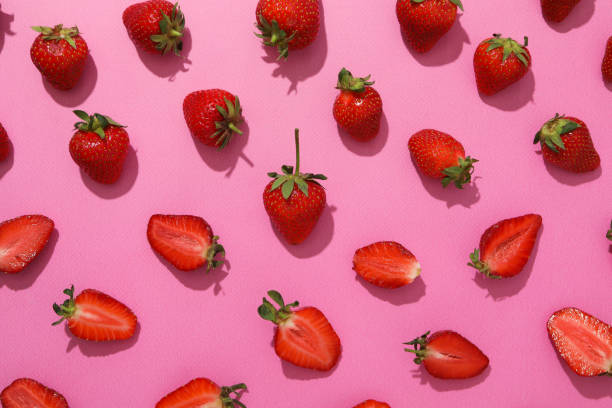 istock Strawberries in pieces and whole on pink background, top view 1944679160