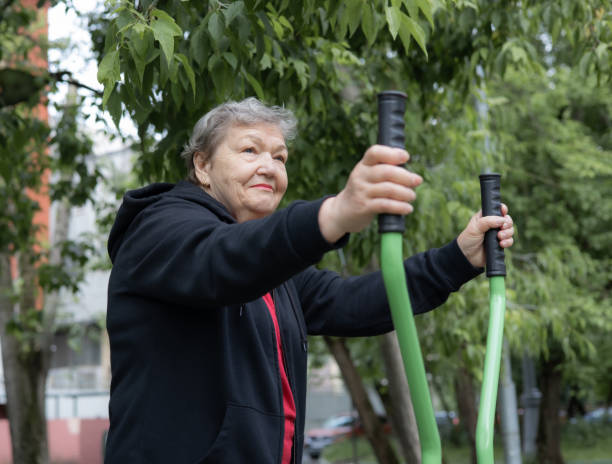 istock Smiling elderly woman is doing exercises on simulator, trainer ellipse outdoors in the yard. Active life of pensioners. Adaptation of pensioners in the modern world. Prevention of mental illness, Alzheimer's disease, sclerosis or dementia. Healthcare 1944680185