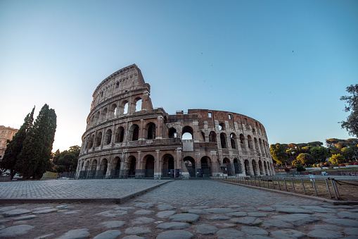 The ancient Colosseum in Rome, Italy, captured at sunrise with clear blue sky and no tourists in sight.