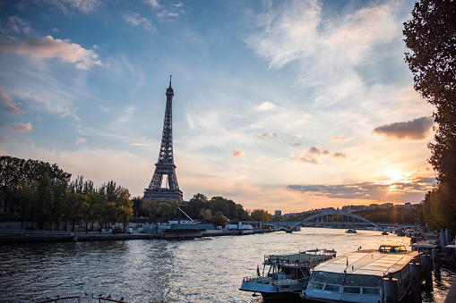 The Eiffel Tower stands tall against a beautiful sunset sky with the Seine River flowing in the foreground, capturing the essence of Paris.