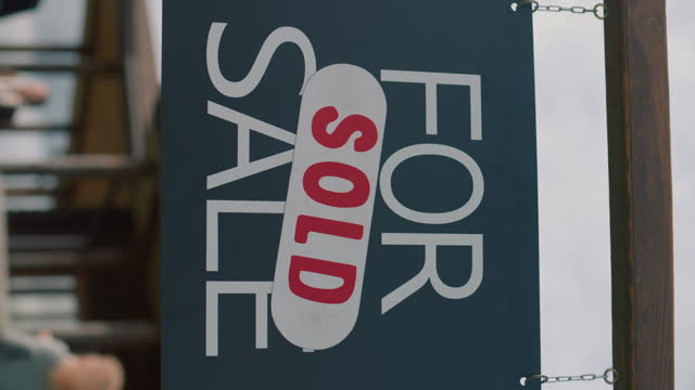 real estate agent comes and places sold sticker on for sale sign