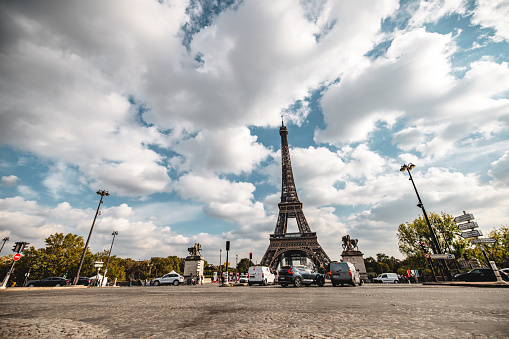 Low angle view of the Eiffel Tower with clear skies and surrounding traffic, capturing the essence of Parisian landmarks.