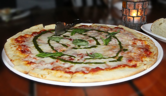 Pizza with mozzarella cheese and basil on a wooden table