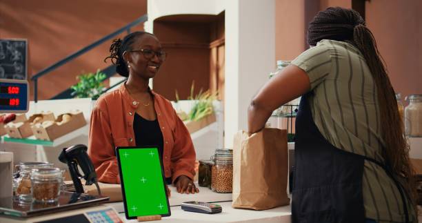 istock Woman approaching checkout with greenscreen on tablet 1944701447