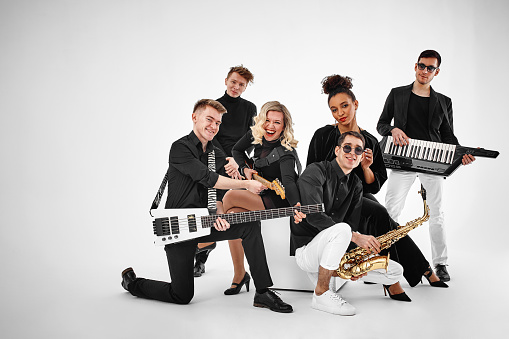 photo of multi ethnic music band in studio.Musicians and woman soloist posing over white background.