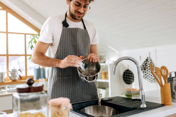 istock Smiling handsome man washing pot in a domestic kitchen 1944708392